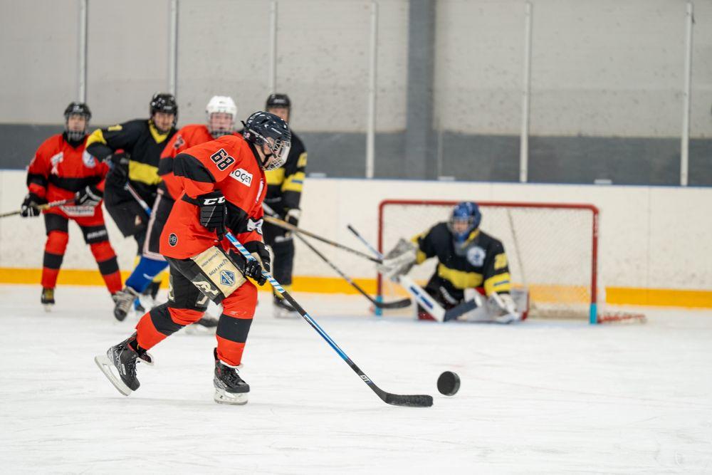 Puna-musta ja musta-kelta -asuisia jääkiekkoilijoita pelaamassa.