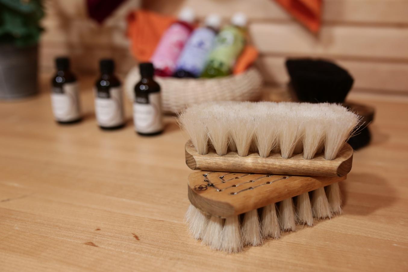 Kaksi jAnnansilmät-Aitan harjaa puupöydällä. Taustalla saunatuoksuja rottinkikorissa. 