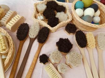 Myyntipöydällä erikokoisia pesuharjoja ja huovutettuja saippuoita.